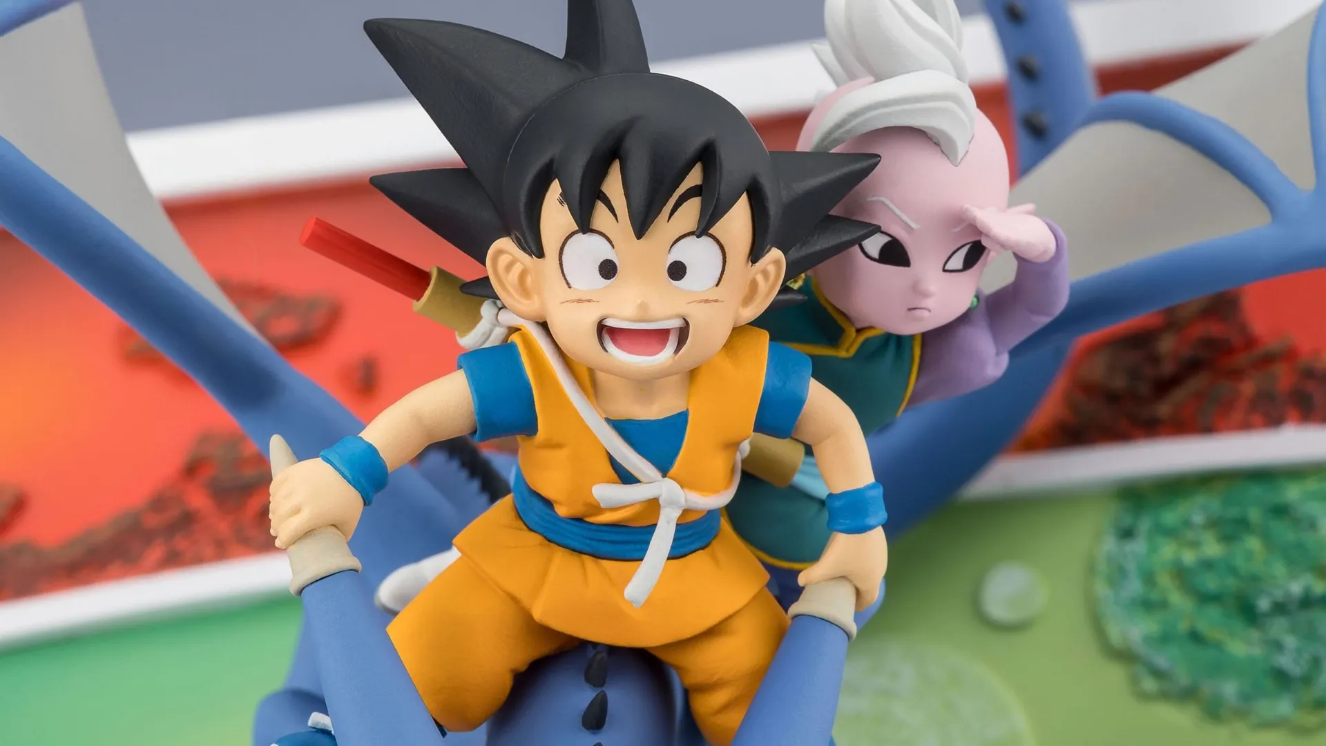 dragon ball son goku and supreme kai figure blog A collectible figurine of mini Son Goku and Supreme Kai riding a blue creature. Goku grins excitedly at the front while Supreme Kai sits behind him, shading his eyes to look ahead.